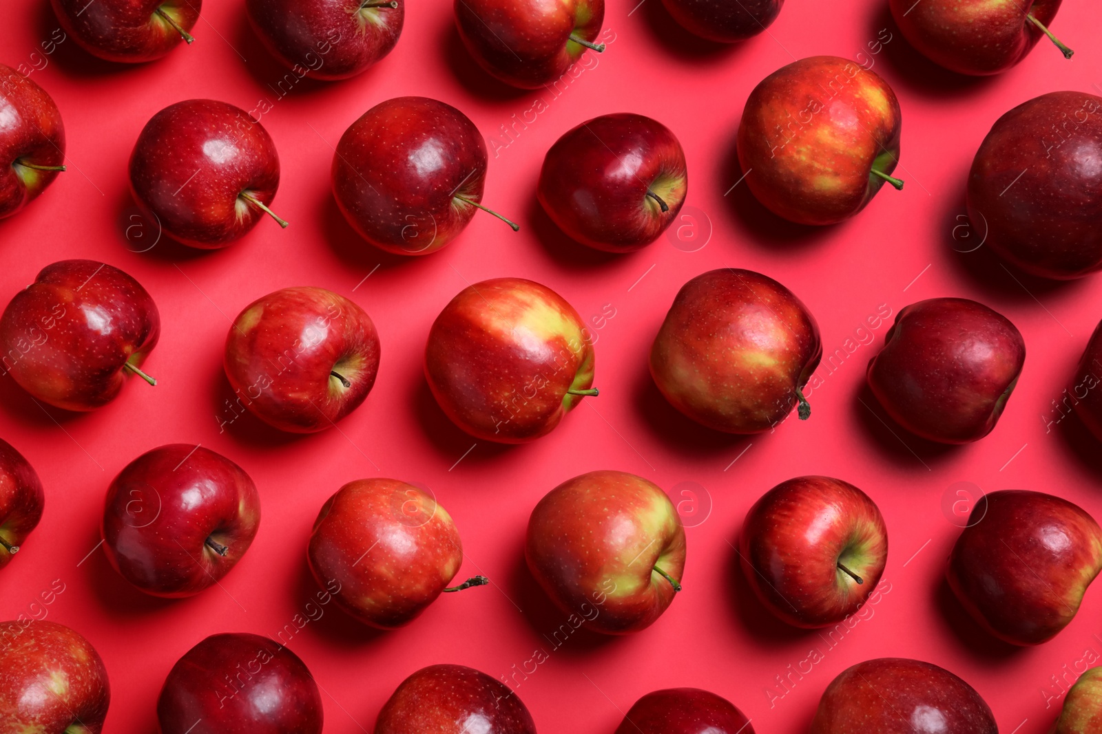 Photo of Many ripe juicy apples on red background, flat lay