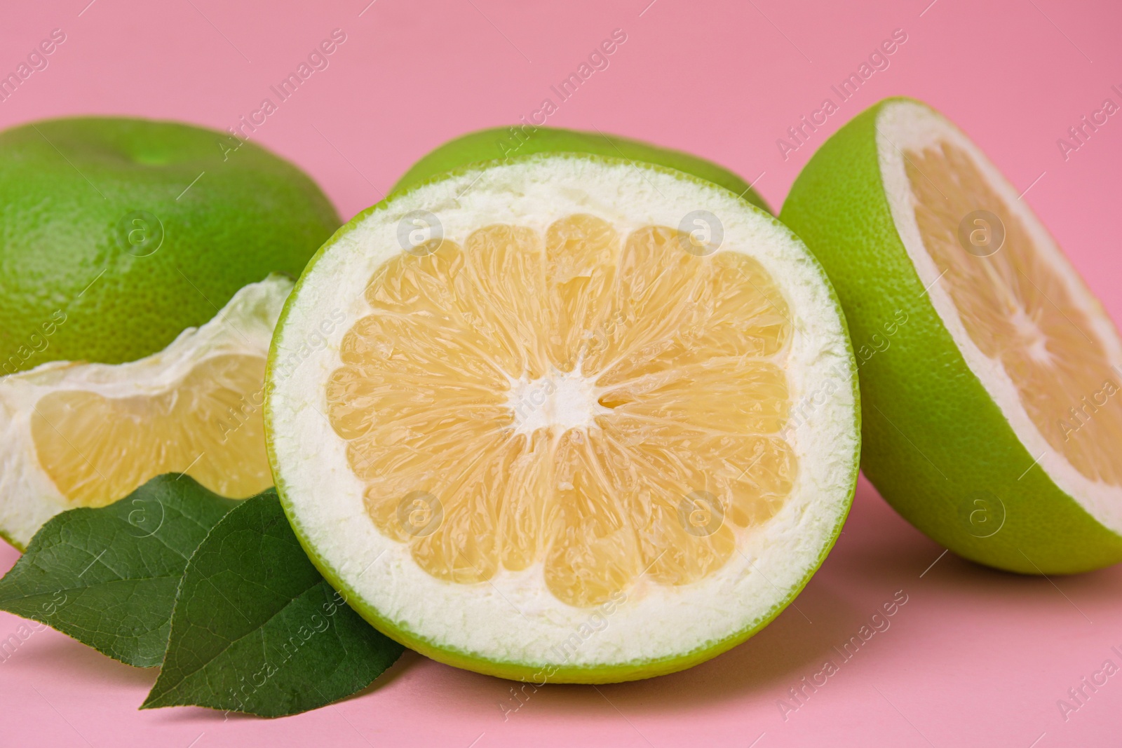 Photo of Tasty whole and cut sweeties on pink background, closeup