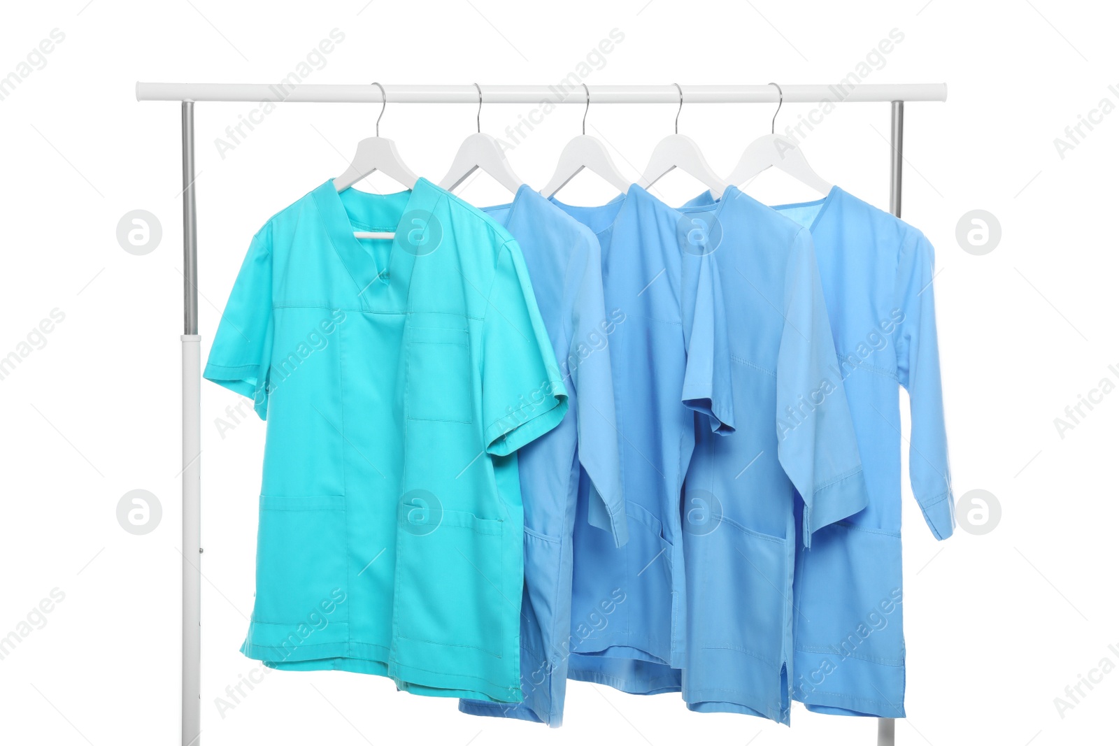 Photo of Turquoise and light blue medical uniforms on rack against white background