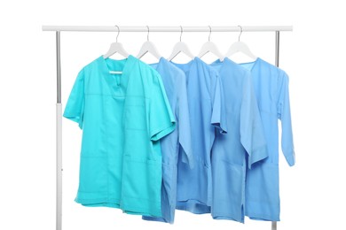 Turquoise and light blue medical uniforms on rack against white background