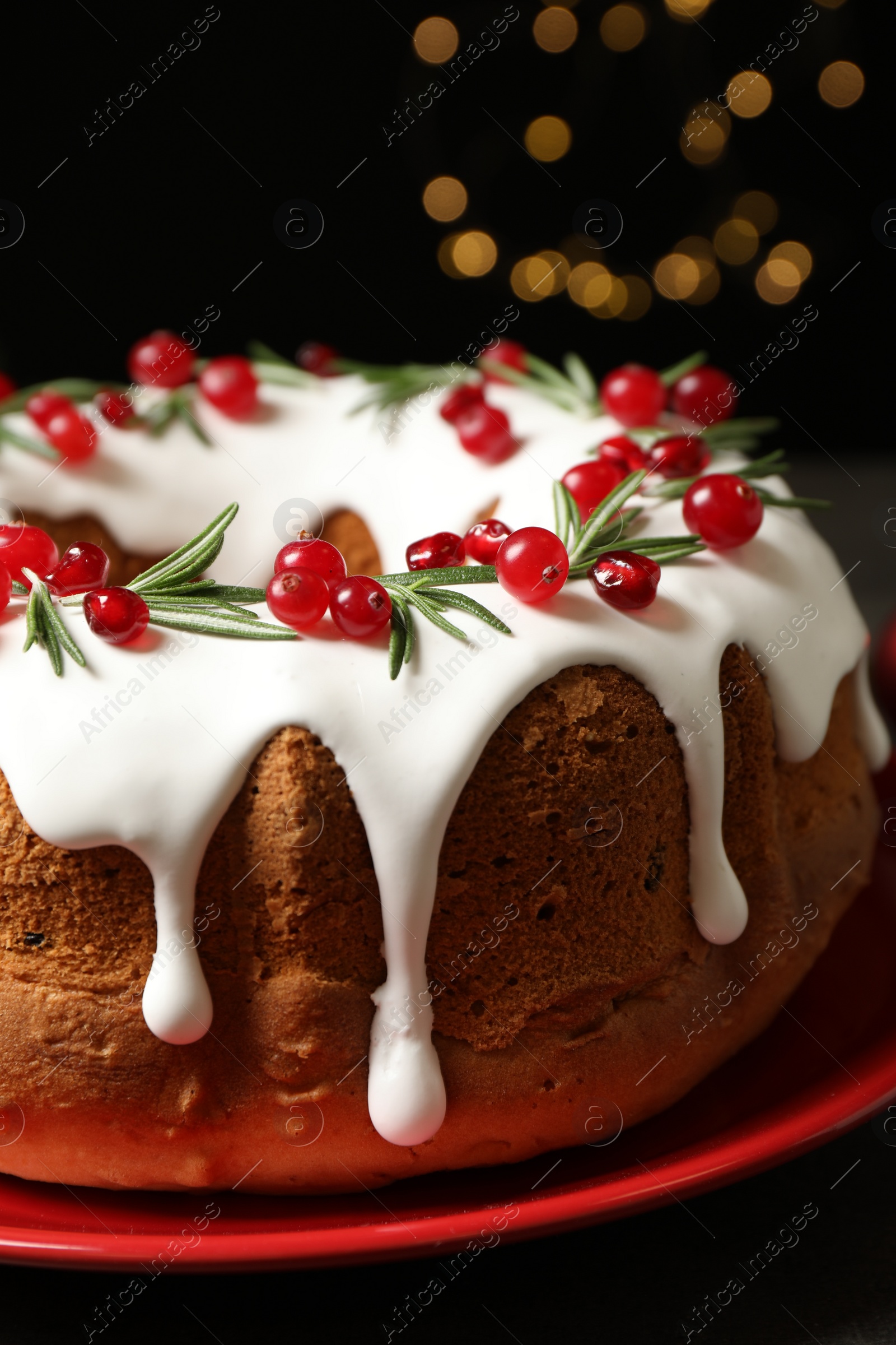 Photo of Traditional Christmas cake decorated with glaze, pomegranate seeds, cranberries and rosemary, closeup