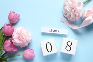 International Women's day - 8th of March. Gift box, wooden block calendar and beautiful flowers on light blue background, flat lay