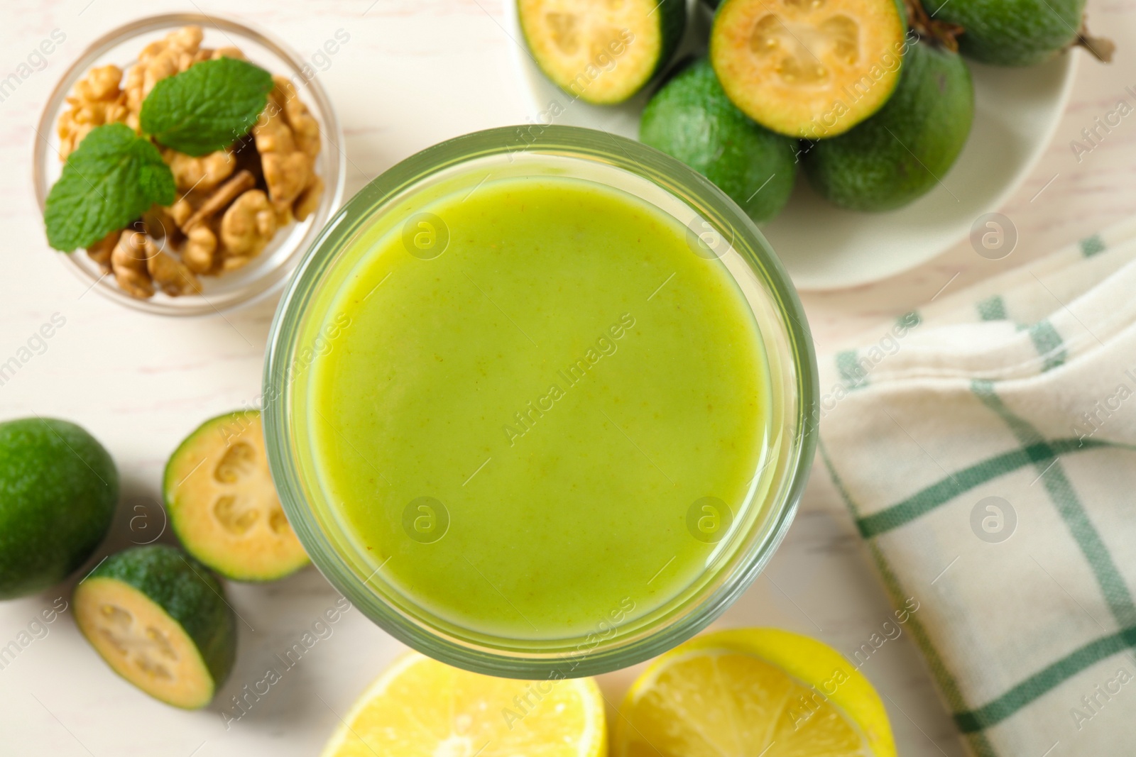 Photo of Flat lay composition with fresh feijoa smoothie in glass on light table. Space for text