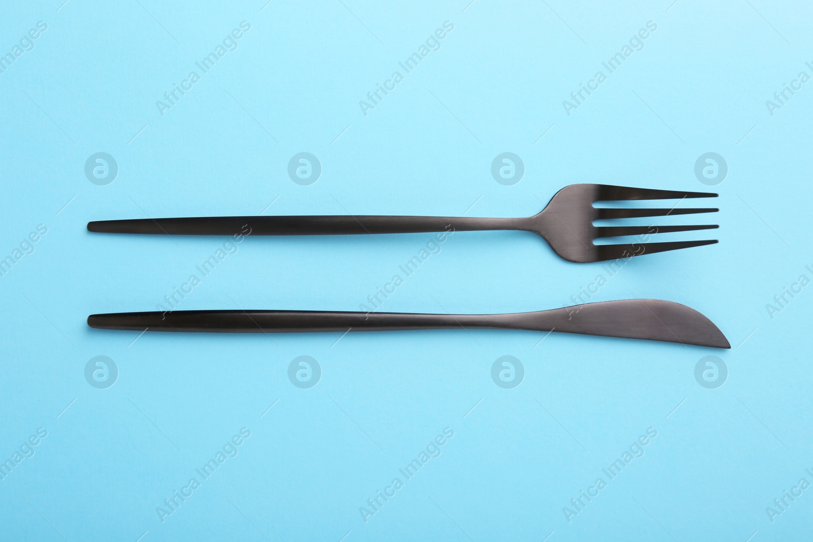 Photo of Stylish cutlery on light blue table, top view