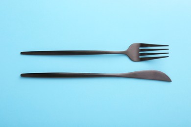 Stylish cutlery on light blue table, top view