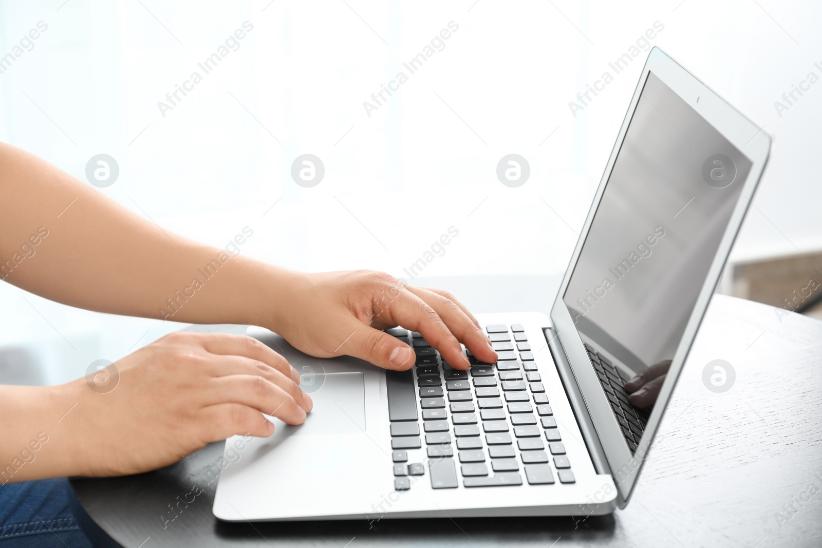 Photo of Young man using laptop at table indoors