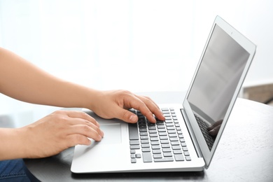 Young man using laptop at table indoors