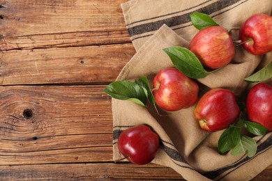 Ripe red apples with leaves on wooden table, flat lay. Space for text