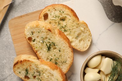 Photo of Tasty baguette with garlic and dill on light grey table, top view
