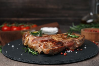 Pieces of delicious fried meat with rosemary and spices on table, closeup