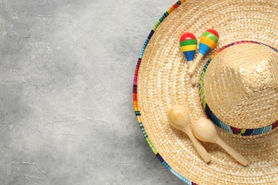 Photo of Mexican sombrero hat and maracas on grey textured background, top view. Space for text