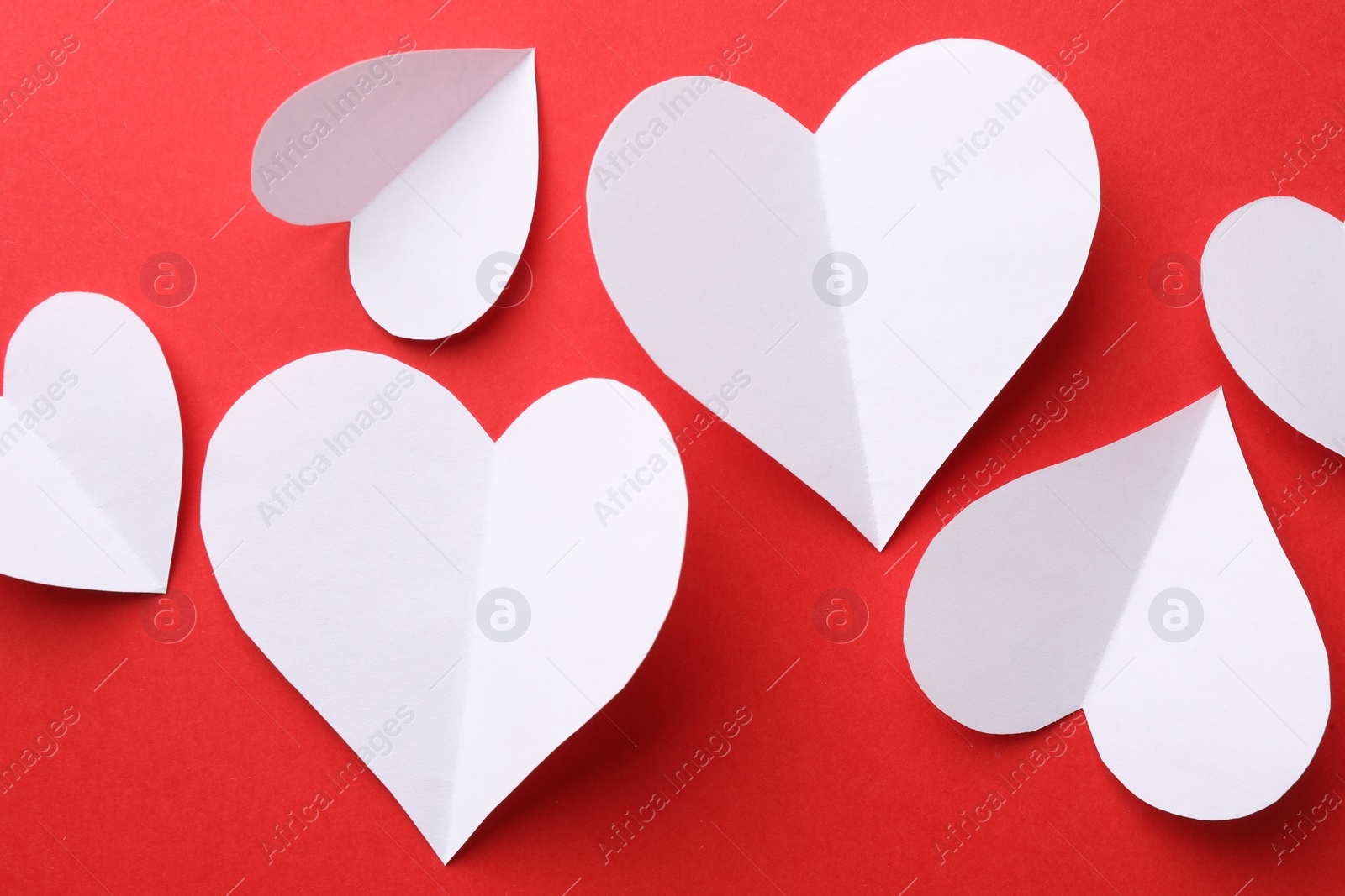 Photo of White paper hearts on red background, flat lay