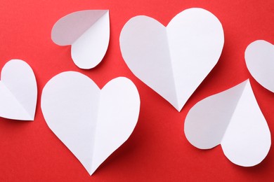 White paper hearts on red background, flat lay