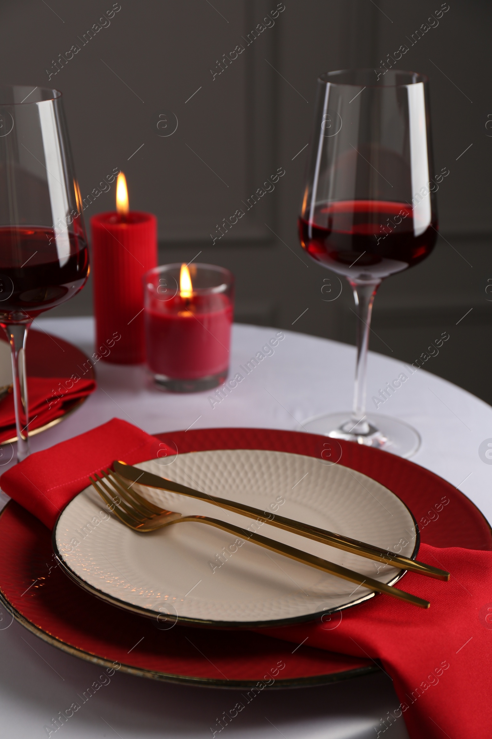 Photo of Place setting with candles on white table. Romantic dinner