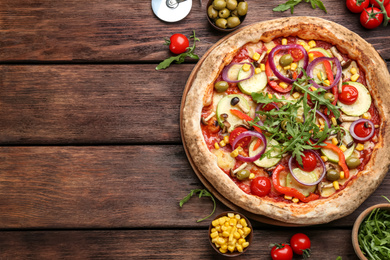 Flat lay composition with vegetable pizza on wooden table. Space for text