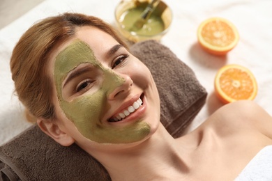 Photo of Beautiful woman with mask on face relaxing in spa salon, closeup