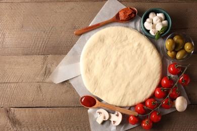 Photo of Pizza dough and products on wooden table, flat lay. Space for text