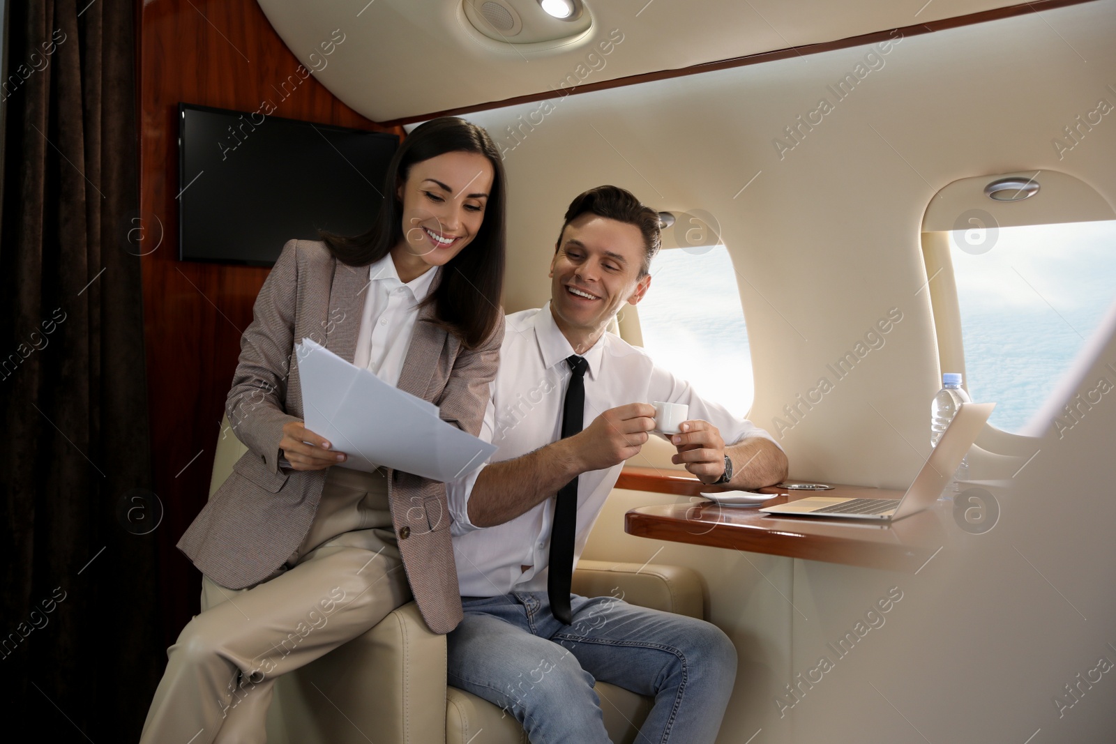 Photo of Colleagues working together in airplane during flight