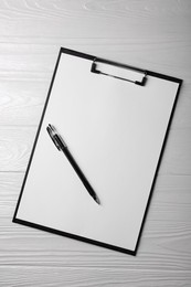 New clipboard with sheet of blank paper and pen on white wooden table, top view