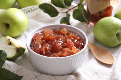 Photo of Bowl of delicious apple jam and fresh fruits on white tablecloth, closeup