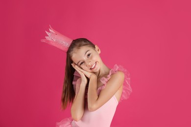 Cute girl in beautiful dress with crown on pink background. Little princess