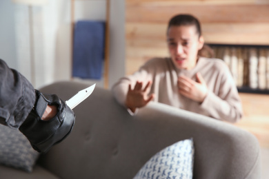 Photo of Man threatening victim with knife indoors, closeup. Dangerous criminal