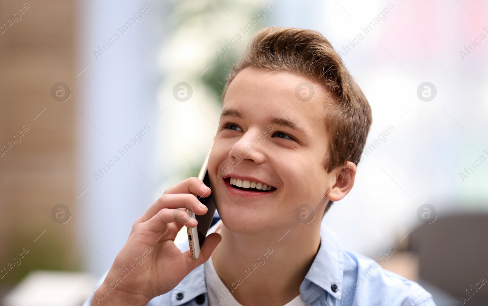 Photo of Happy teenage boy talking on phone at home