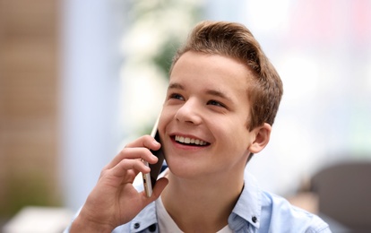 Happy teenage boy talking on phone at home