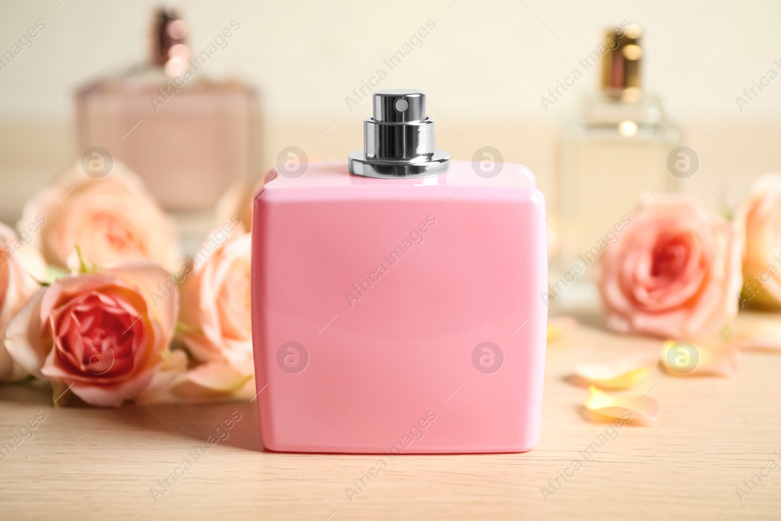 Photo of Bottles of perfume and beautiful flowers on wooden table