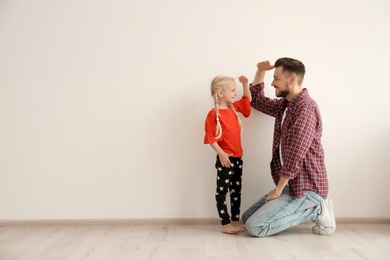 Photo of Young man and little girl measuring their height indoors