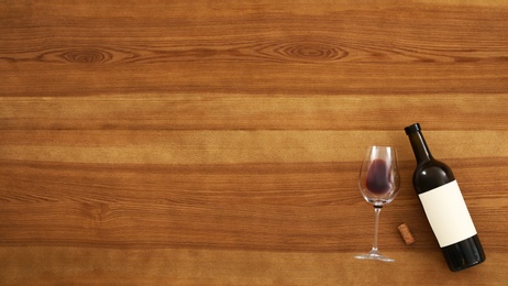 Photo of Flat lay composition with bottle of wine and elegant glass on wooden background. Space for text