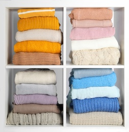 Photo of Many knitted winter clothes stacked on shelves on white background