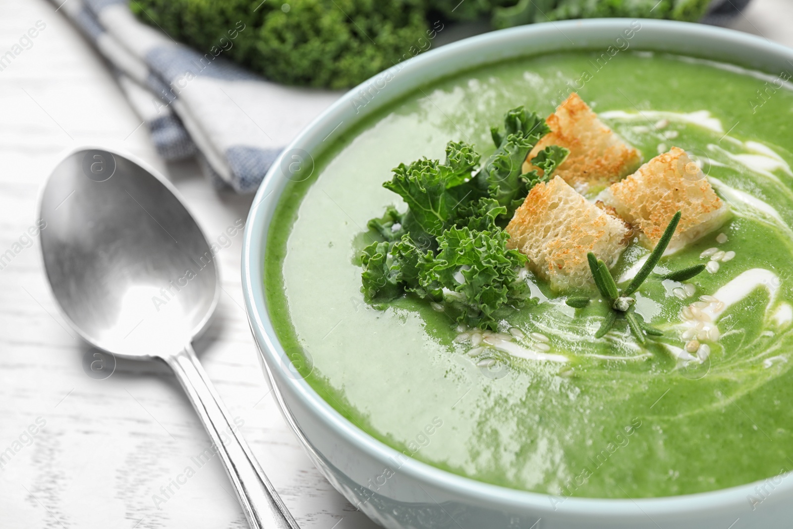 Photo of Tasty kale soup served on white wooden table, closeup