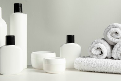 Different bath accessories and towels on white table against grey background