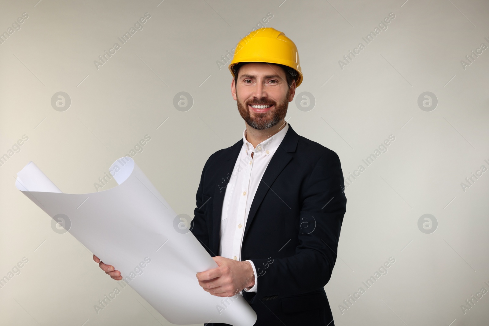 Photo of Architect in hard hat with draft on gray background