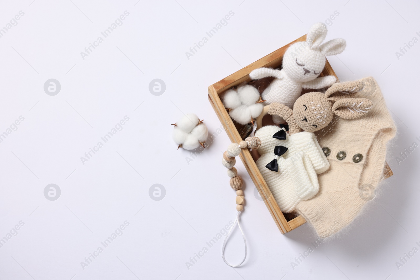 Photo of Different baby accessories and clothes in wooden crate on white background, top view. Space for text