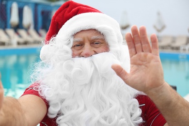 Authentic Santa Claus taking selfie near swimming pool outdoors