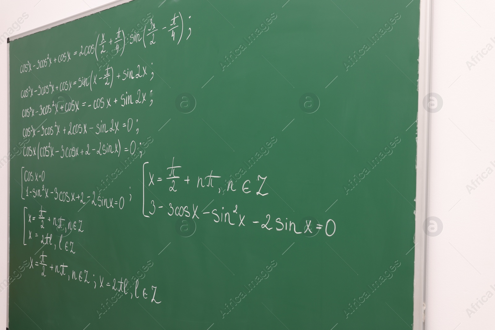 Photo of Many different math formulas written on green chalkboard