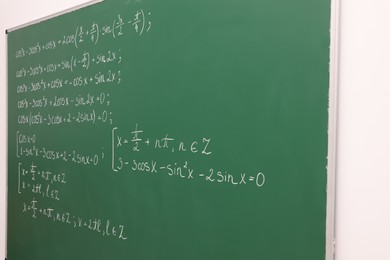 Many different math formulas written on green chalkboard