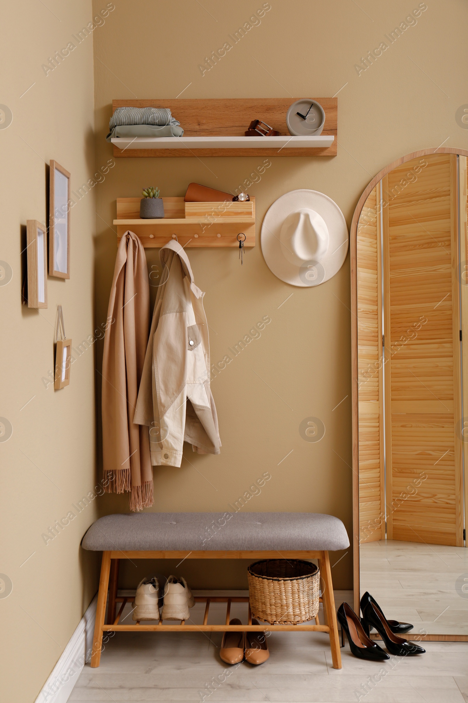 Photo of Hallway interior with stylish furniture, accessories and wooden hanger for keys on beige wall