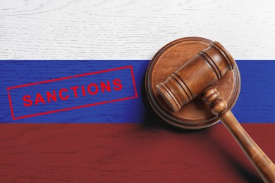 Image of Judge's gavel on wooden background in color of Russian flag, top view. Concept of sanctions against Russia
