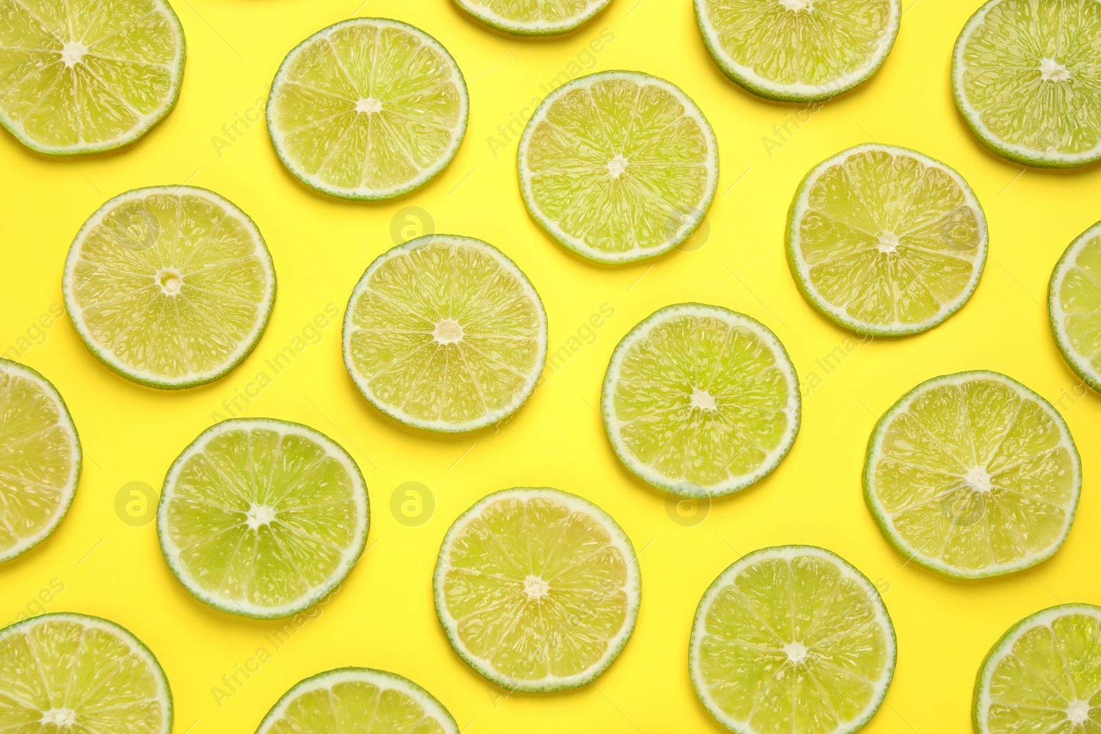 Photo of Fresh juicy lime slices on yellow background, flat lay