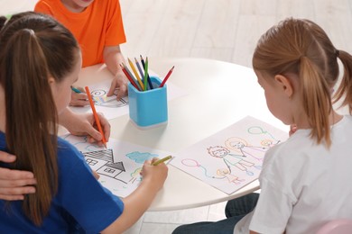 Photo of Cute little children drawing pictures at desk in kindergarten. Playtime activities
