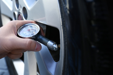 Mechanic checking tire air pressure at car service, closeup