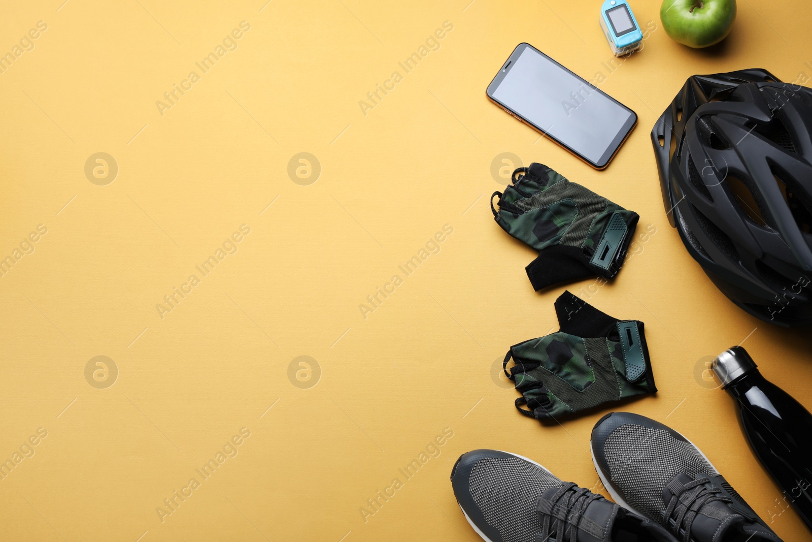 Photo of Flat lay composition with different cycling accessories on pale orange background, space for text