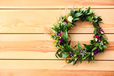 Photo of Beautiful wreath made of flowers and leaves on wooden background, top view. Space for text