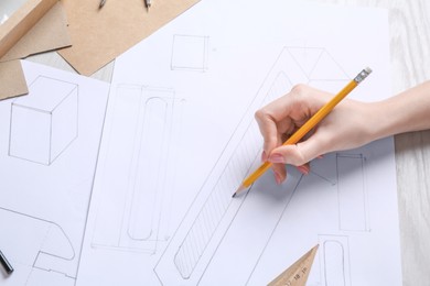 Photo of Woman creating packaging design at light wooden table, top view