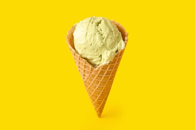 Photo of Delicious ice cream in waffle cone on yellow background