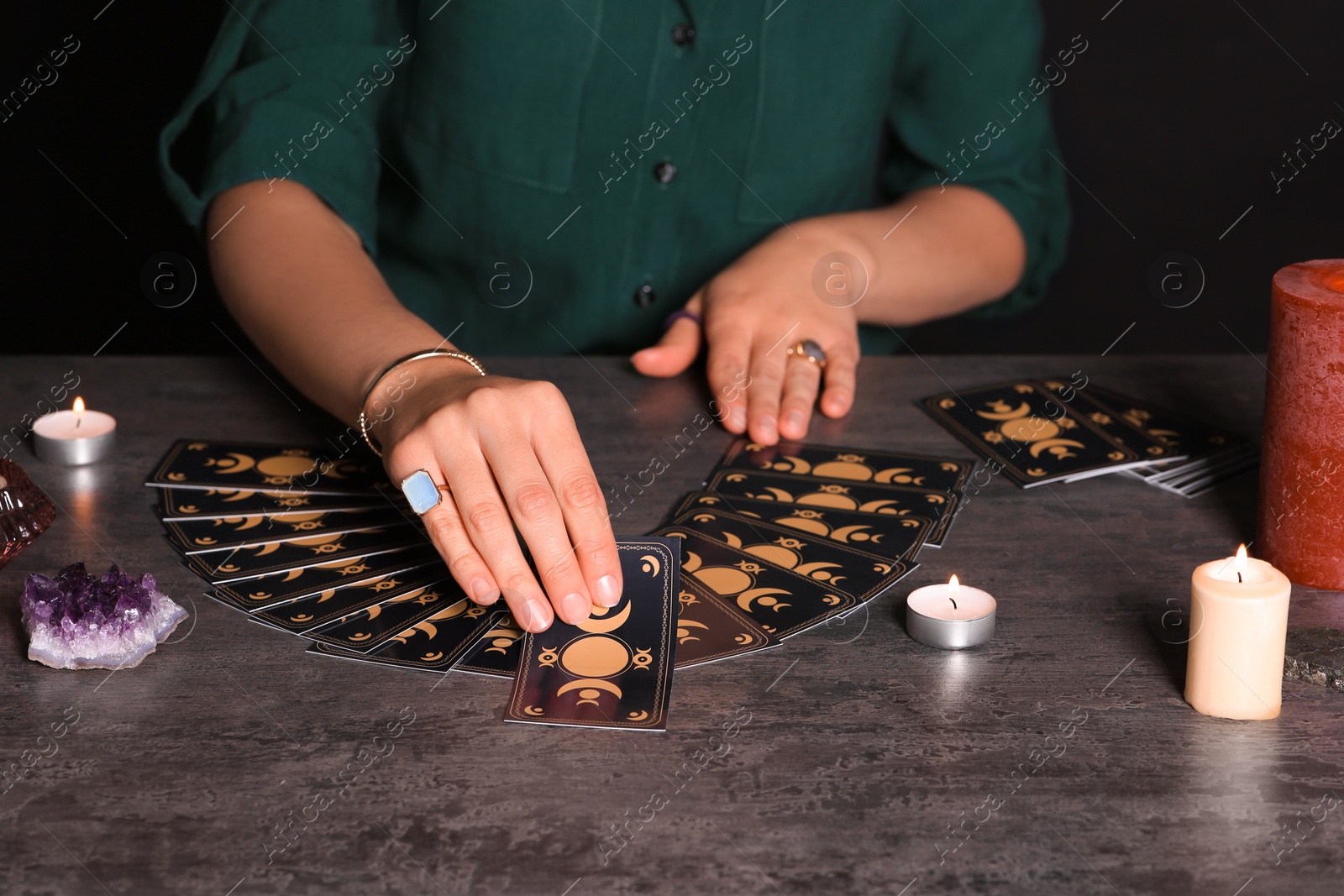 Photo of Soothsayer predicting future with tarot cards at table in darkness, closeup