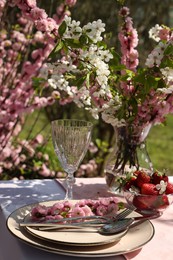 Photo of Stylish table setting with beautiful spring flowers in garden